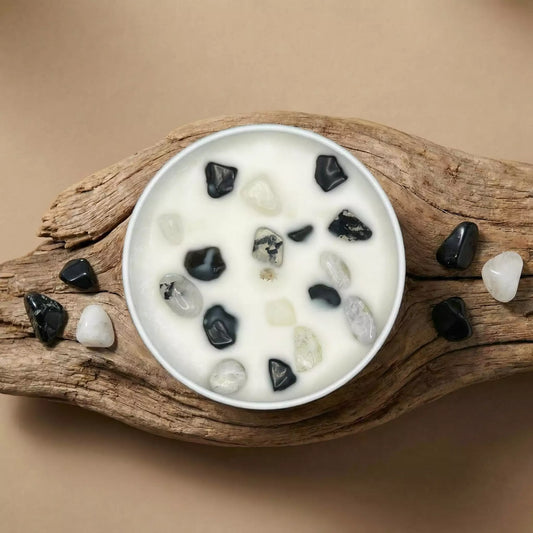 Sojas vaska svece ar melno obsidiānu un mēnessakmeni enerģētiskai aizsardzībai, skats no augšas uz koka fona, MarreDeco roku darbs