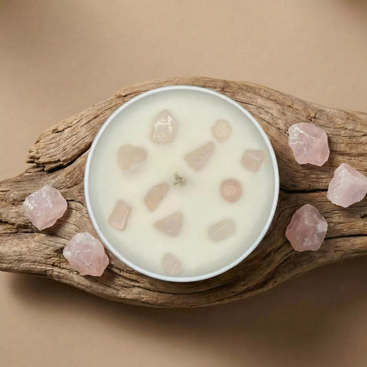 Skats no augšas uz MarreDeco nodoma sveci ar rozā kvarca kristāliem, kas novietota uz dabīga koka pamatnes un ieskauta neapstrādātos rozā kvarca akmeņos