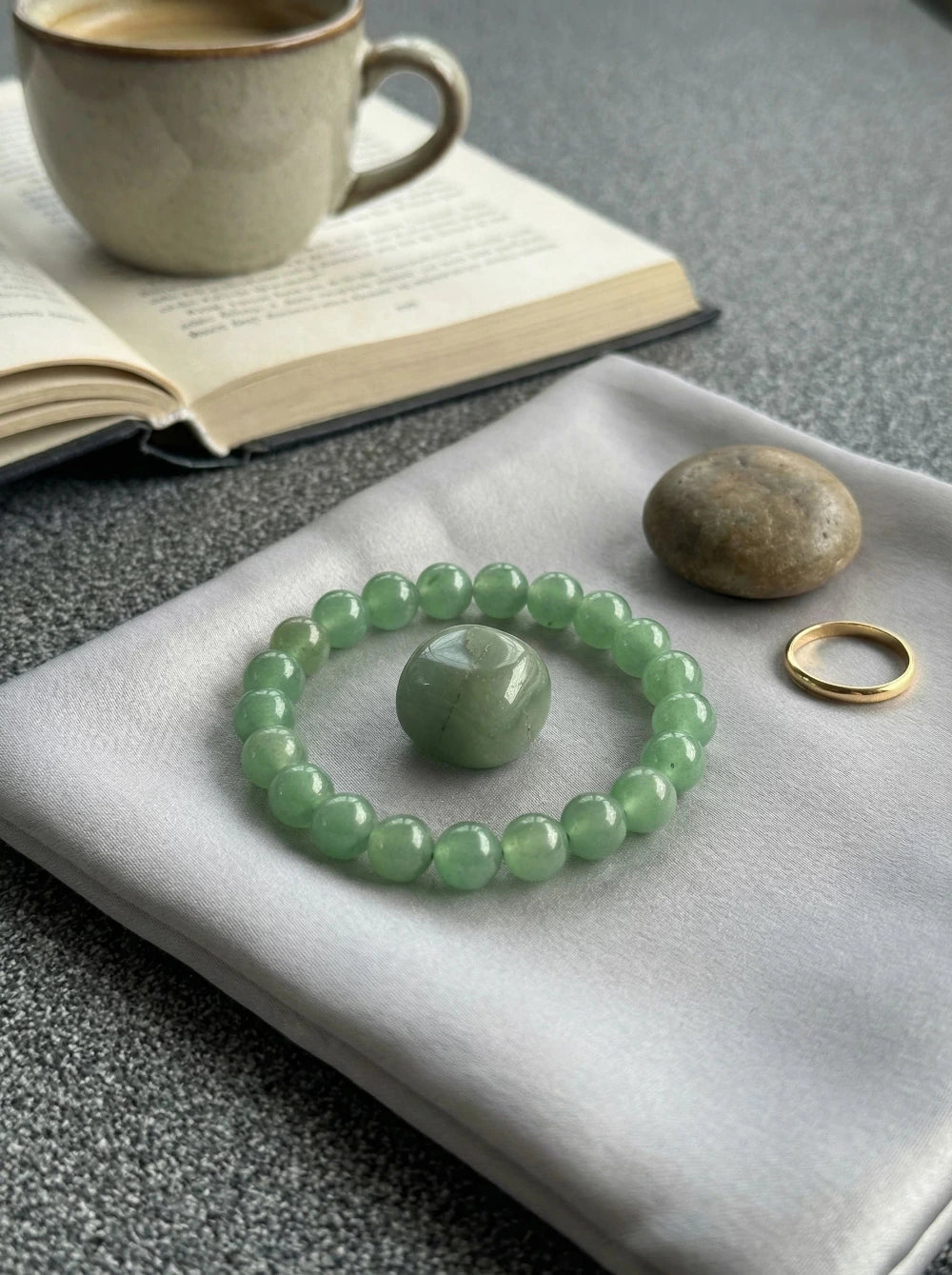 Zaļā aventurīna pērlīšu aproce un pulēts kristāls mājīgā kompozīcijā ar grāmatu un kafiju, MARREdeco akmens rotaslietas