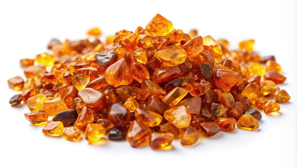 Neapstrādāti dabīgā Baltijas dzintara gabaliņi uz balta fona – MarreDeco sveču un dekoru izejvielas siltumam un enerģijai