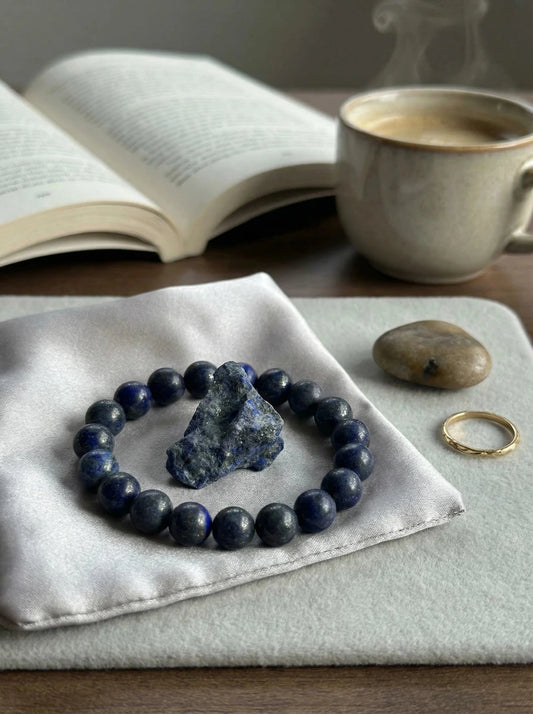 Zilā lazurīta (Lapis Lazuli) dabīgo akmeņu pērlīšu aproce un neapstrādāts kristāls uz satīna maisiņa, MARREdeco juvelierizstrādājumu kolekcija