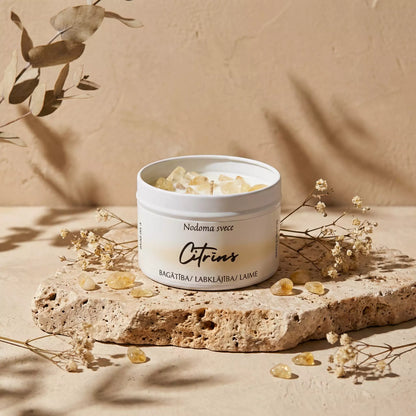 MarreDeco nodoma svece "Citrīns" bagātībai un laimei, dekorēta ar citrīna kristāliem uz dabīga travertīna akmens pamatnes siltā, saulainā atmosfērā