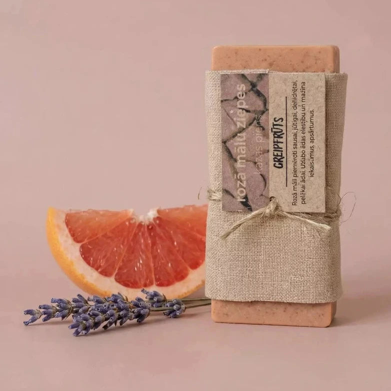 Dabīgas rozā mālu un kazas piena ziepes "Greipfrūts", ietītas lina audumā un dekorētas ar svaigu greipfrūta šķēli un lavandas ziediem.