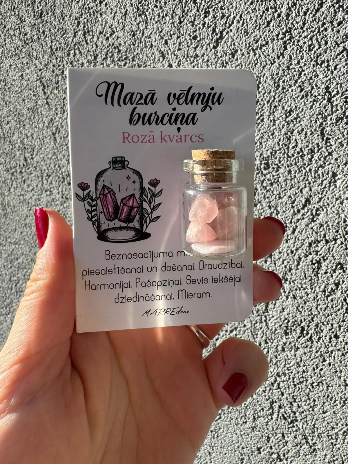 MarreDeco "Mazā vēlmju burciņa" ar rozā kvarca kristāliem mīlestībai, harmonijai un iekšējai dziedināšanai, turēta rokā.
